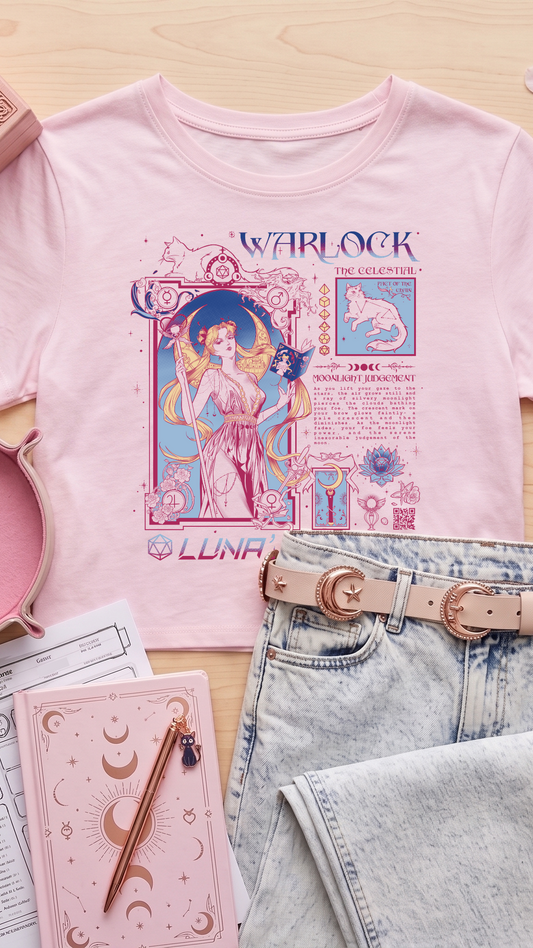 A styled flat-lay of a light pink graphic T-shirt featuring a celestial Warlock design, paired with light-wash jeans, a pink moon belt, and pink accessories on a light wood background.